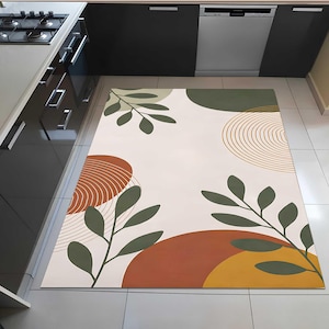 Puede incluir: Una alfombra rectangular con un diseño abstracto. La alfombra presenta un fondo crema con grandes formas orgánicas en tonos verdes, naranjas y amarillos. Los patrones de ramas con hojas y círculos concéntricos también están presentes.