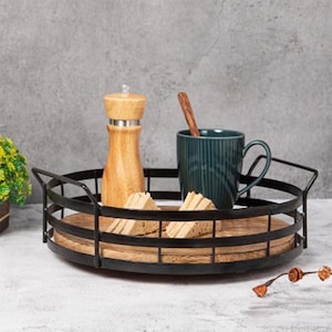 Puede incluir: Una bandeja redonda para servir con un marco de metal negro y una base de madera. Contiene un molinillo de pimienta de madera, una taza verde azulado con una cuchara de madera y trozos de pan. Ideal para servir alimentos y bebidas.