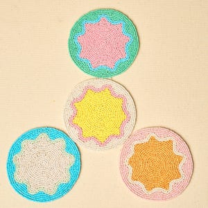 May include: Four circular coasters crafted from small glass beads. Each coaster features a central star-shaped pattern with scalloped edges. The color combinations include mint green with pink, cream with yellow, bright blue with cream, and pink with orange.