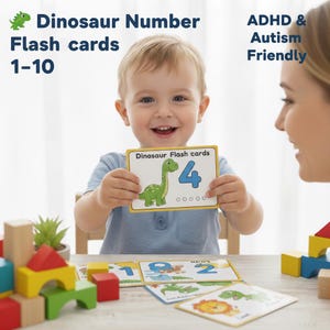 Pode incluir: Uma criança segura um cartão com um dinossauro verde e o número 4. O cartão faz parte de um conjunto rotulado como "Dinosaur Number Flash cards 1-10". A imagem também inclui o texto "ADHD & Autism Friendly". Blocos coloridos estão sobre a mesa.