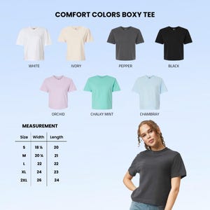 May include: A Comfort Colors boxy tee available in white, ivory, pepper, black, orchid, chalky mint, and chambray. A measurement chart lists sizes S through 2XL with widths from 18.25 to 26 inches and lengths from 20 to 24 inches for each size.