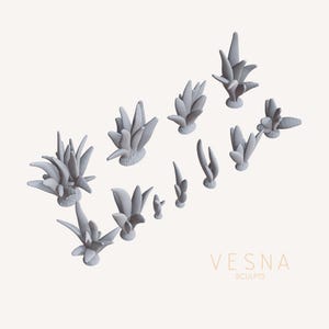 May include: A collection of gray, stylized plant sculptures in various sizes and shapes. The sculptures have a textured base and pointed leaves. The word "VESNA" and the word "SCULPTS" are printed in a light brown color.