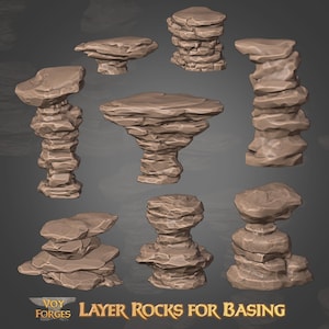 May include: A collection of layered rock formations in various shapes and sizes, rendered in shades of brown and tan. The image includes text that reads "LAYER ROCKS FOR BASING" and the logo "VOY FORGES". These rocks are designed for basing miniatures.