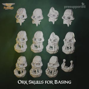 Puede incluir: Una colección de once cráneos de orco en miniatura de color blanco roto y una pieza de mandíbula separada para bases. Los cráneos presentan colmillos prominentes, cuencas oculares profundas y arcos superciliares marcados. Texto "Voy Forges" y "presupported".