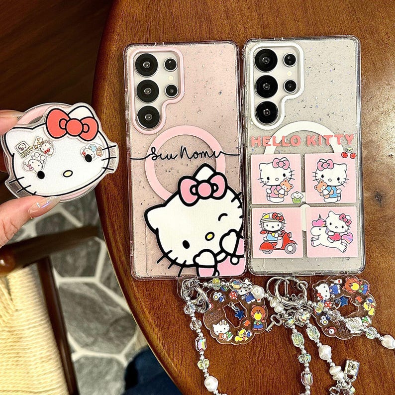 Peut inclure: Coques de t&eacute;l&eacute;phone roses avec des motifs Hello Kitty, un support pop-up et des porte-cl&eacute;s assortis. Un &eacute;tui pr&eacute;sente un grand motif Hello Kitty, l'autre plusieurs petites images. Les porte-cl&eacute;s pr&eacute;sentent divers personnages de dessins anim&eacute;s.
