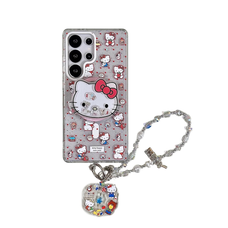 Może przedstawiać: Przezroczyste etui na telefon z motywem Hello Kitty, z dużą twarzą Hello Kitty i mniejszymi ilustracjami postaci. Zawiera srebrną bransoletkę z zawieszkami z wisiorkiem. Etui na telefon ma napis "kitty happy new year".