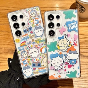 以下が含まれることがあります： 夏をテーマにしたカラフルなデザインの透明な携帯電話ケース2つ。1つのケースには漫画のキャラクター、「Chillin' Trio」というテキスト、その他の夏のグラフィックが描かれています。もう1つのケースには漫画のキャラクターと「Summer Fun！」というテキストが描かれています。