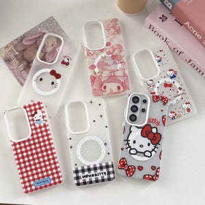 May include: A collection of phone cases featuring Hello Kitty and My Melody designs. The cases showcase various patterns, including gingham, stars, and floral motifs, with a clear area for the phone's camera. The color palette includes red, pink, and white.