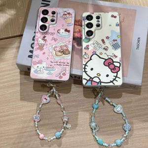 May include: Two phone cases with Hello Kitty designs, one pink and one white, with matching beaded bracelets. The pink case has a dessert theme, while the white case features school supplies. The bracelets have pink, blue, and clear beads.