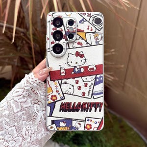 Peut inclure: Coque de t&eacute;l&eacute;phone blanche avec un motif Hello Kitty. La coque pr&eacute;sente un motif r&eacute;p&eacute;t&eacute; d'illustrations Hello Kitty, des accents rouges et le texte "Hello Kitty". La coque a une d&eacute;coupe pour l'appareil photo.