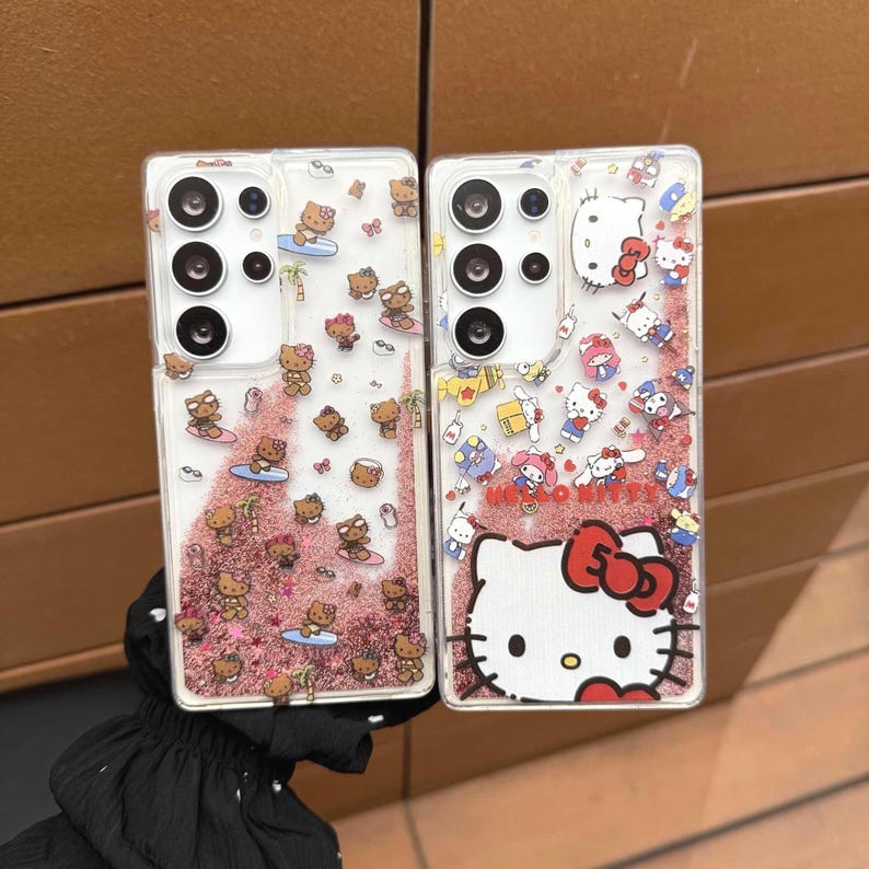May include: Two clear phone cases with Hello Kitty designs. One case features Hello Kitty characters surfing and the other has a large Hello Kitty face with a red bow. Both cases have a glittery pink background.