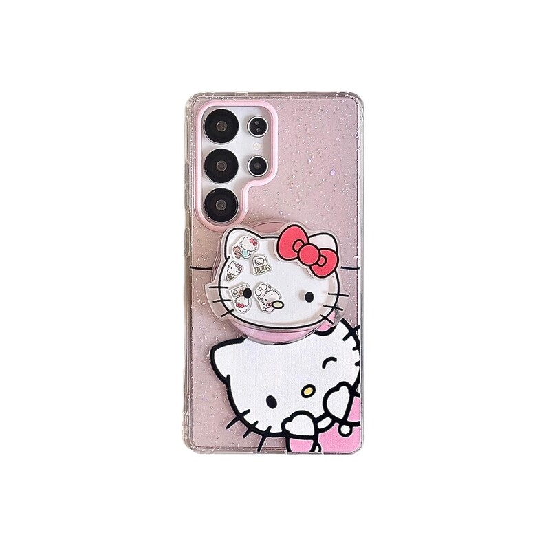 Peut inclure: Une coque de t&eacute;l&eacute;phone rose avec un motif Hello Kitty. L'&eacute;tui a un fond clair et scintillant et une poign&eacute;e pop-up avec un visage Hello Kitty et un n&oelig;ud rouge. La cam&eacute;ra du t&eacute;l&eacute;phone est visible en haut.