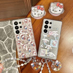 Może przedstawiać: Przezroczyste etui na telefony z postaciami z kresk&oacute;wek. Jedno etui ma powtarzający się wz&oacute;r Hello Kitty, drugie Cinnamoroll i Hello Kitty. Pokazano r&oacute;wnież uchwyty do telefon&oacute;w i breloki do kluczy Hello Kitty.