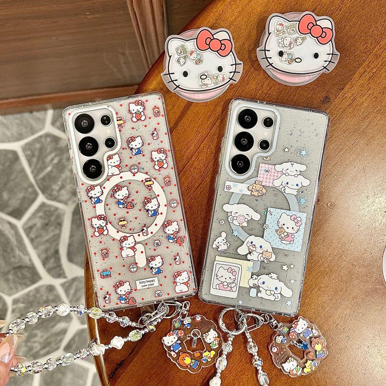 Może przedstawiać: Przezroczyste etui na telefony z postaciami z kresk&oacute;wek. Jedno etui ma powtarzający się wz&oacute;r Hello Kitty, drugie Cinnamoroll i Hello Kitty. Pokazano r&oacute;wnież uchwyty do telefon&oacute;w i breloki do kluczy Hello Kitty.
