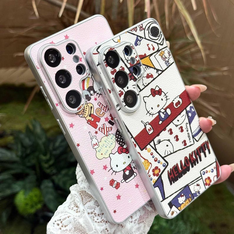 Peut inclure: Deux coques de t&eacute;l&eacute;phone avec des motifs Hello Kitty. L'une est rose avec un motif d'&eacute;toiles r&eacute;p&eacute;t&eacute;es et des graphiques Hello Kitty. L'autre est blanche avec un motif de collage Hello Kitty, avec le texte "Hello Kitty". Les deux coques ont des bords argent&eacute;s.