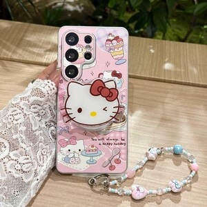 May include: Pink phone case featuring a Hello Kitty design with a red bow, desserts, and the text "You will always be a happy holiday." Includes a beaded wrist strap with pink, blue, and clear beads.