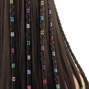 Puede incluir: Primer plano de cabello castaño trenzado adornado con cuentas metálicas de colores. Las cuentas son de varios colores, incluyendo dorado, plateado, rosa, verde, azul y morado. El cabello está peinado en múltiples trenzas.