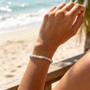 May include: A delicate bracelet composed of small, rounded beads in a variety of soft pastel colors including light blue, pink, yellow, and white. The beads are strung together in a continuous circular pattern, resting snugly around the wrist.