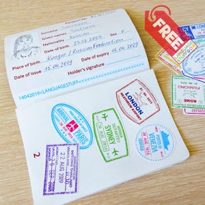 Könnte beinhalten: Ein geöffneter Reisepass mit handschriftlichem Namen und Geburtsdatum, umgeben von farbenfrohen Reisestempeln aus Städten wie London, Paris und Sydney. Ein rotes Etikett mit dem Wort "FREE" ist ebenfalls sichtbar.