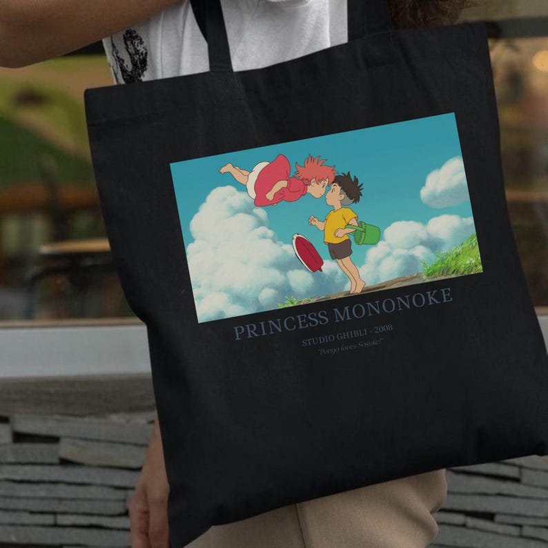 May include: Black tote bag featuring a colorful illustration from the animated film "Princess Mononoke." The image shows two characters in a vibrant outdoor scene with text that reads "Princess Mononoke" and "Studio Ghibli 2008."
