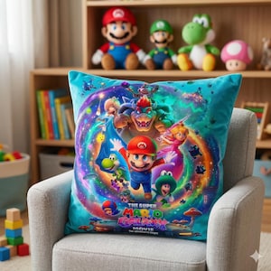 May include: A teal square pillow featuring a colorful graphic from "The Super Mario Bros. Movie." The design includes Mario, Luigi, Princess Peach, Bowser, and Yoshi, set against a swirling galaxy background. Plush toys of Mario, Luigi, and Yoshi are visible in the background.