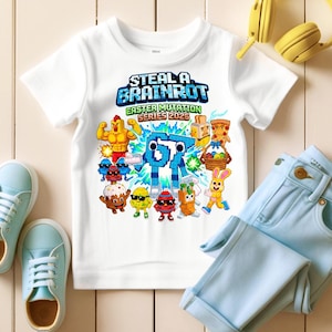 May include: White t-shirt with a colorful graphic featuring the text "STEAL A BRAINROT" and "EASTER MUTATION SERIES 2026". The graphic includes various cartoon characters. Light blue jeans and sneakers are also visible.