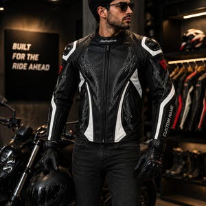 May include: A black leather motorcycle jacket featuring white accents, intricate white stitching patterns, a stand-up collar, and protective shoulder armour. The sleeve displays the text CUSTOM NAME, while the collar features the text RawHideWorks.
