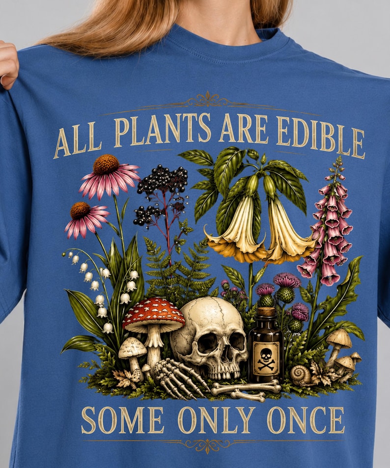 May include: Blue t-shirt with a botanical illustration featuring flowers, mushrooms, a skull, and the text "ALL PLANTS ARE EDIBLE, SOME ONLY ONCE". The design includes a poison bottle and a skeleton hand.