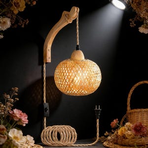May include: A woven rattan pendant lamp with a wooden arm and a coiled rope cord. The lamp has a spherical shade and a warm, inviting glow. The design is rustic and natural, with a focus on texture and organic materials.