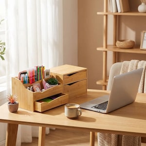 May include: A bamboo desk organizer with multiple compartments filled with pens, markers, and small office supplies. A small two-drawer bamboo storage unit and a laptop are also on the wooden desk. A small potted plant and a cup of coffee complete the scene.