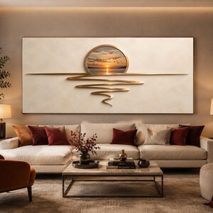 Op de afbeelding: Een groot rechthoekig wandkunstwerk met een getextureerde crèmekleurige achtergrond en een centrale ronde inzet die een zonsondergang boven water toont. Een metalen gouden horizontale lijn strekt zich uit met golvende lijnen.