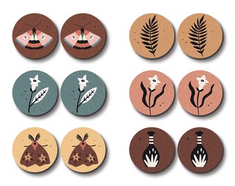 Puede incluir: Conjunto de ocho amuletos de madera cortados con láser con varios diseños, incluyendo mariposas, hojas, flores y jarrones. Los amuletos son en tonos de marrón, beige, amarillo, rosa y azul.