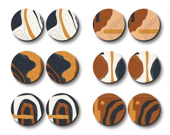 Könnte beinhalten: Neun lasergeschnittene Holz Kreise mit abstrakten Designs in Braun-, Weiß- und Schwarztönen. Die Designs beinhalten Wellenlinien, Bögen und geometrische Formen.