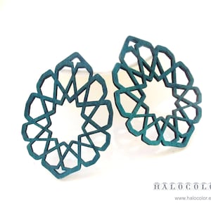 May include: A pair of teal blue geometric earrings with a starburst design. The earrings are made of wood and have a laser cut pattern.