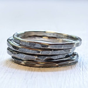 May include: Four silver hammered stacking rings. The rings are stacked on top of each other and are made of a hammered metal.