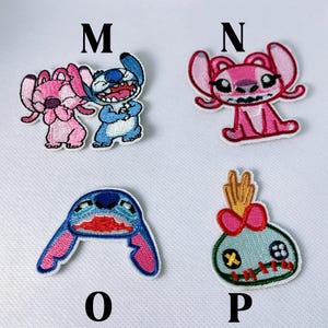 K&ouml;nnte beinhalten: Gestickte Aufn&auml;her mit Figuren aus einem beliebten Zeichentrickfilm. Die Aufn&auml;her zeigen Stitch in Blau und Rosa sowie Angel in Rosa. Die Aufn&auml;her sind mit den Buchstaben M, N, O und P beschriftet.