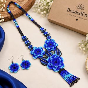 May include: A beaded necklace and matching earring set featuring intricate blue and black floral designs. The necklace includes a long beaded chain, three-dimensional flower pendants, black beaded leaves, and a blue and black fringe tassel.