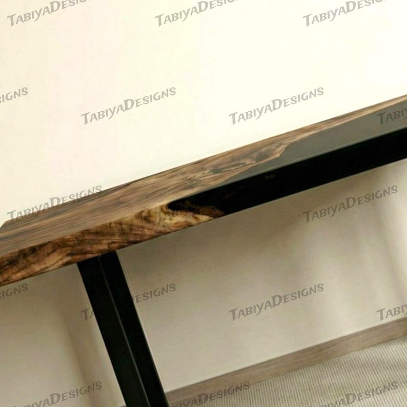 May include: A close-up of a wooden table with a dark, natural wood grain finish. The table has a black metal frame and legs. The wood has a rich, brown colour with lighter streaks. The table is a modern design.