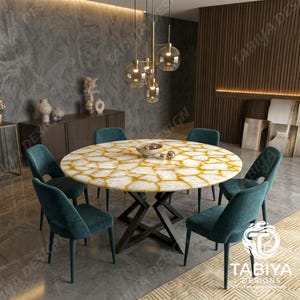May include: A round dining table with a white and gold-veined stone top and a black metal geometric base, surrounded by six teal velvet upholstered chairs. A modern pendant light fixture with five glass globes hangs above the table.
