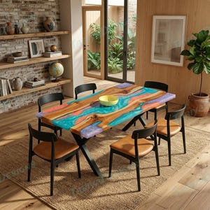 May include: A rectangular wooden dining table with a colorful epoxy resin river design in shades of blue, orange, and purple. The table is supported by black metal legs and surrounded by black chairs with brown leather seats. A yellow bowl sits on the table.