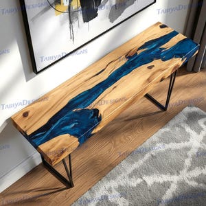 May include: A wooden bench with a river of blue epoxy resin running through the center. The bench has a natural wood grain finish and black metal legs. The bench is approximately 60 inches long.