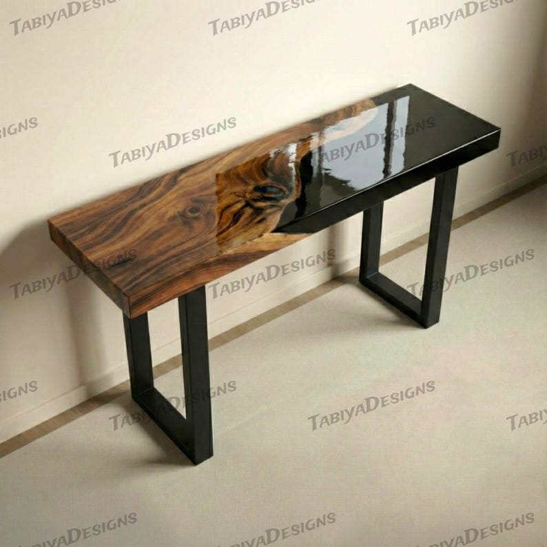 May include: A rectangular console table with a live edge wood top and a black epoxy resin section. The table has a black metal frame. The wood grain is visible. The table is approximately 152 cm long.