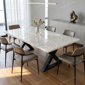 May include: A rectangular dining table with a white, patterned surface and black metal legs. Six brown leather chairs surround the table. A vase of flowers sits in the center. The table is approximately 72 inches long.