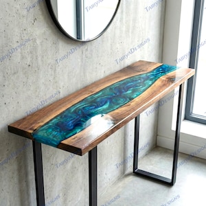 Può includere: Una consolle in legno con un fiume di resina epossidica blu e turchese al centro. Il tavolo ha una finitura in legno scuro e gambe in metallo nero. Il tavolo è lungo circa 122 cm.