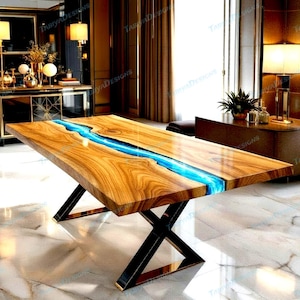 May include: A wooden dining table with a blue resin river design. The table has a natural wood grain finish and sits on a black metal base with gold accents. The table is rectangular and appears to be in a modern dining room.