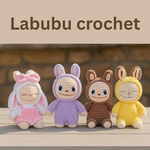 May include: Four handmade crochet dolls in a row. The dolls are in pink, purple, brown, and yellow. Each doll has a smiling face and a hood with bunny ears. The text "Labubu crochet" is at the top.