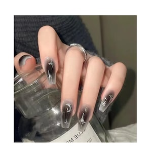 May include: A white ceramic mug with a black handle and the text "But First, Coffee" in a bold, black font. The mug is set against a neutral background, highlighting its simple design.