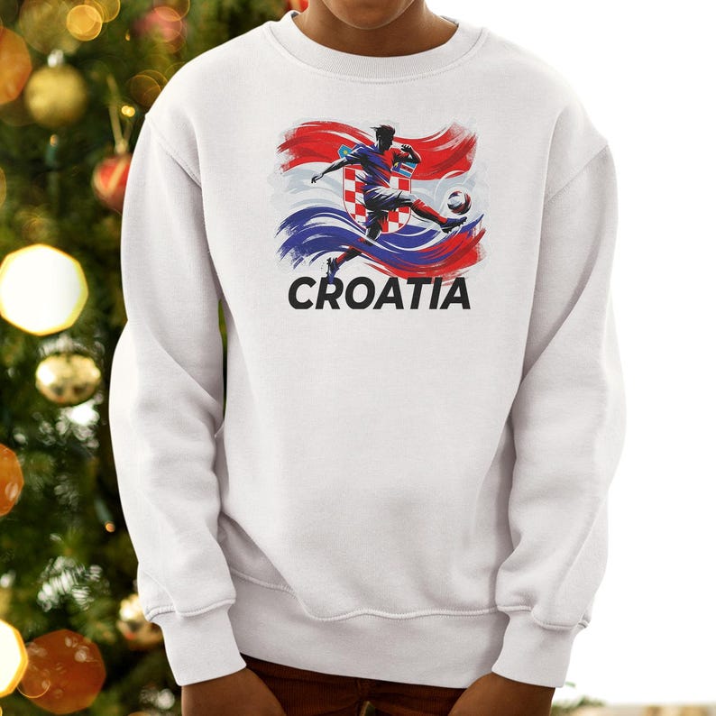A person wearing a white sweatshirt with a graphic of a soccer player kicking a ball, along with the word "Croatia" printed on it.