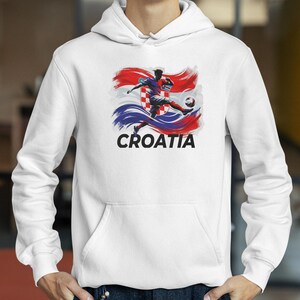 A white hoodie with a graphic design depicting a soccer player kicking a ball, with the word "Croatia" written below the image.