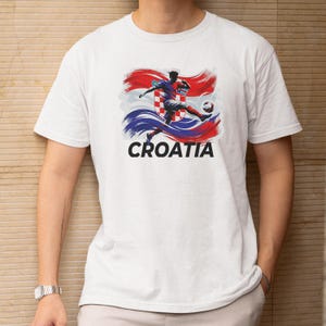 A white t-shirt with a graphic design depicting a soccer player in action, along with the word "Croatia" written below the image.